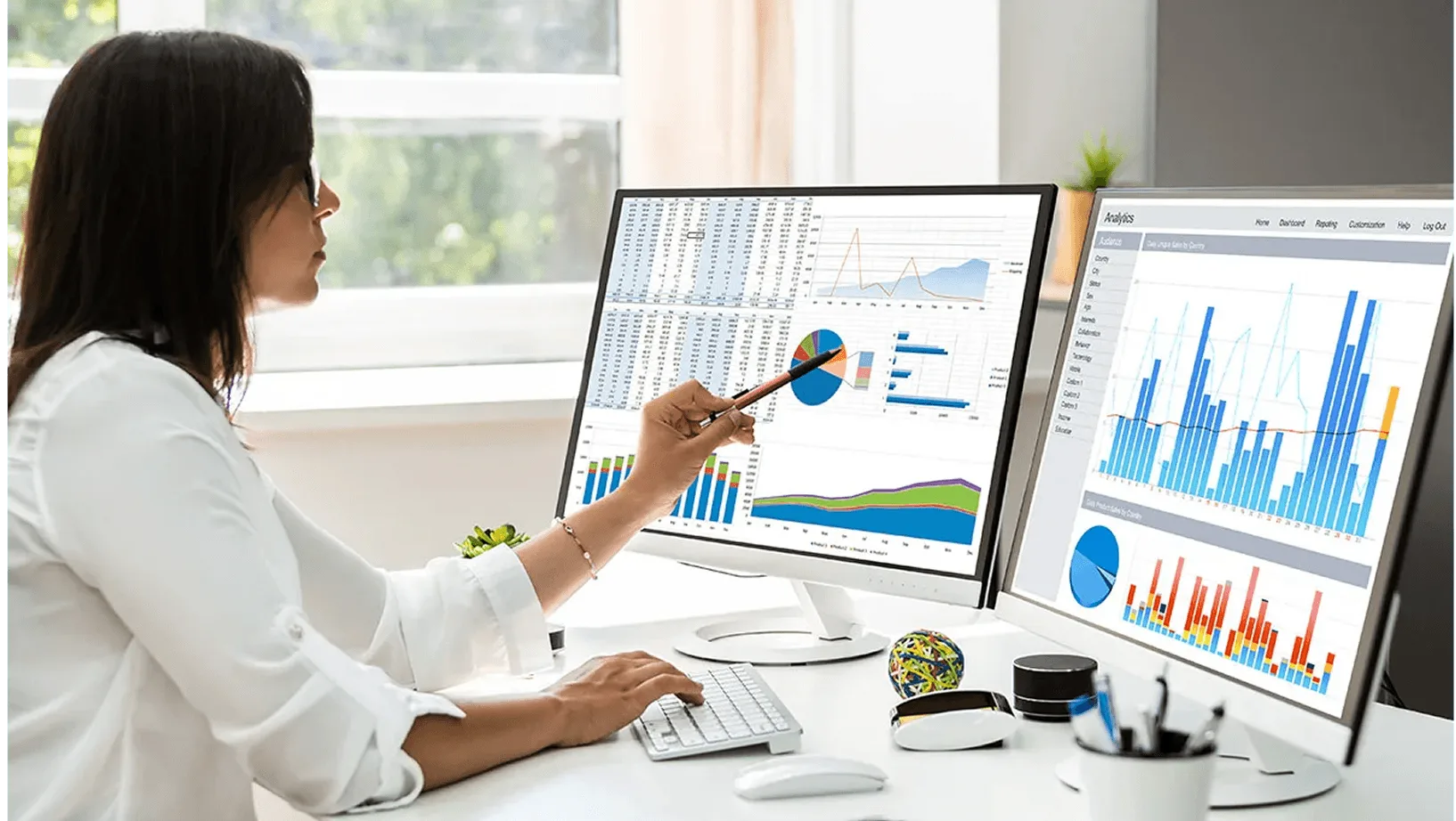 Data analyst reviewing charts and business dashboards across dual monitors